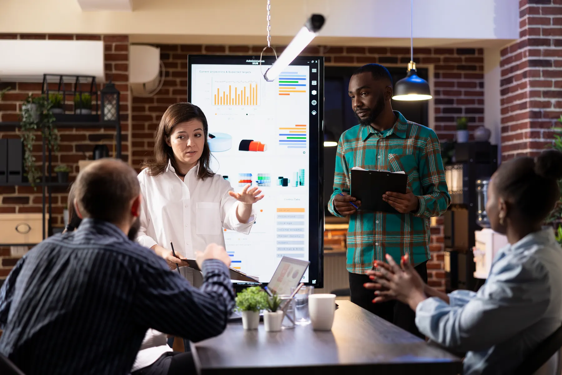 Two colleagues presenting growth charts on a large screen